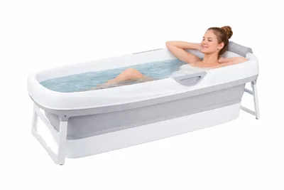 A woman is relaxing in a portable bathtub filled with water.