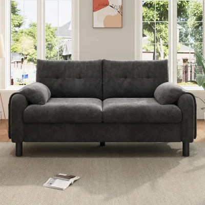 A gray sofa is placed in a well-lit room with large windows in the background.