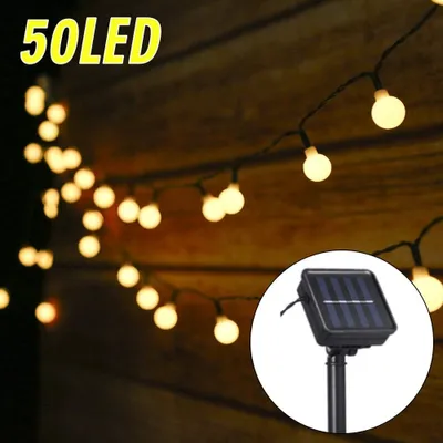 A string of solar-powered LED lights with a solar panel in the foreground, set against a wooden background.