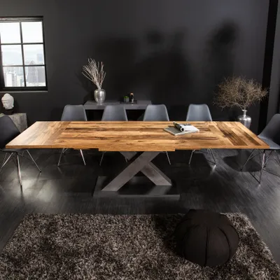 A dining room with a large wooden table and chairs, set against a dark wall.