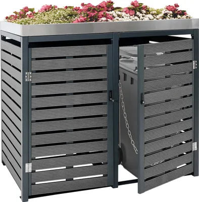 A modern, dark gray outdoor bin enclosure with a green roof covered in pink and white flowers.