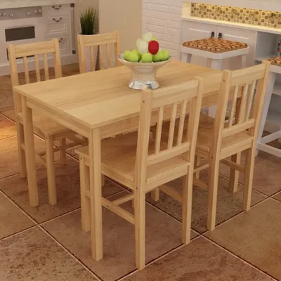 A wooden dining table with four chairs, set in a room with a kitchen counter in the background.
