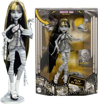 A Monster High doll, Cleo de Nile, is shown both out of its packaging and inside its retail box. The packaging features a film reel motif and promotional graphics.