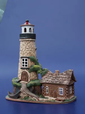 Ein handgefertigtes Keramikmodell eines Leuchtturms und eines kleinen Hauses. Farbpalette erdig.