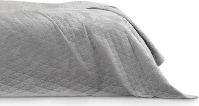 A close-up view of a quilted bedspread draped over a bed.