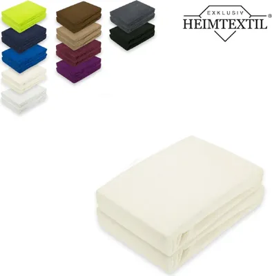 A stack of folded cream-colored fitted sheets is shown in the foreground, with a collage of stacked fabric swatches in various colors in the upper left corner. A logo and brand name are in the upper right corner.