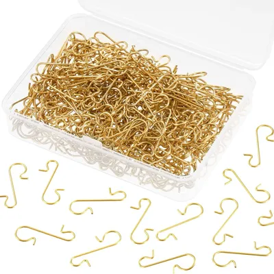 A clear, well-lit studio shot of gold-colored ornament hooks in a clear plastic box and scattered around it on a white background.