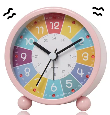 Produktbild von 1 Stück Kinderwecker in rosa Farbe aus lackiertem Metall mit analogem Zifferblatt, leisem Quarzwerk und integriertem Nachtlicht. Dieser Lernwecker unterstützt Kinder spielerisch beim Erlernen der Uhrzeit durch farbcodierte Zahlen und fördert gleichzeitig die Farbwahrnehmung. Der lautlose Betrieb ohne Ticken sorgt für ruhige Schlafphasen und konzentriertes Lernen. Dank großer, intuitiver Tasten auf der Rückseite können Kinder selbstständig Zeit und Weckfunktion einstellen. Das sanfte Nachtlicht erleichtert d