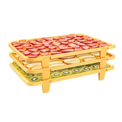 A three-tiered food dehydrator rack filled with sliced fruits.