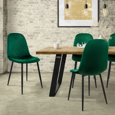 A dining room scene with a wooden table and four dark green velvet chairs.