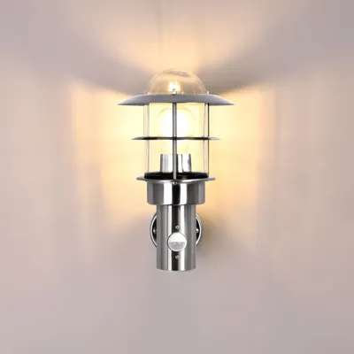 A modern outdoor wall lamp with a motion sensor is mounted on a light gray wall.