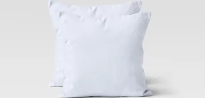 Two white square pillows are shown against a light gray and white background.