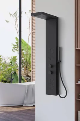 A modern bathroom with a black shower panel system mounted on a white wall, next to a large window overlooking a lush garden and a white bathtub.