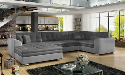 A modern living room with a large sectional sofa, kitchen area, and large windows.