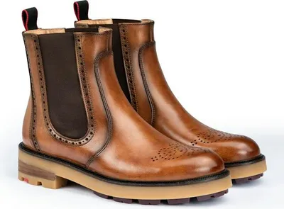 A pair of brown leather Chelsea boots with brogue detailing and a thick sole, presented against a white background.