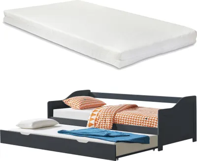 A white mattress is shown above a dark gray daybed with a trundle bed pulled out. The daybed has orange and white patterned bedding and a white pillow. The trundle bed has a white pillow and a blue towel.