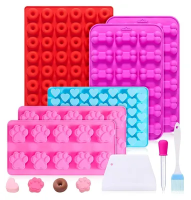 A collection of silicone molds for baking dog treats, along with a few sample treats and baking accessories.