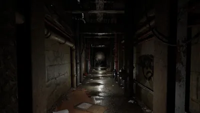 A dark, grimy, and wet corridor with pipes and graffiti on the walls.