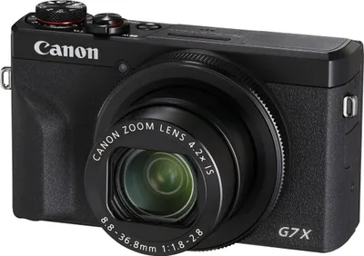 A black Canon PowerShot G7 X Mark III digital camera is shown from a front-facing angle against a white background.