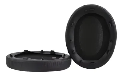 Two black ear pads for headphones are shown against a white background. One is lying flat, showing the underside with mounting clips, and the other is standing upright, showing the padded surface.