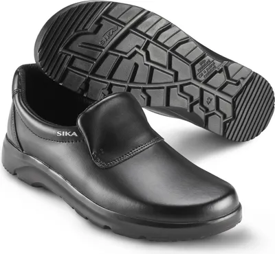 A pair of black Sika brand work shoes, one shoe is upright and the other is upside down showing the sole.