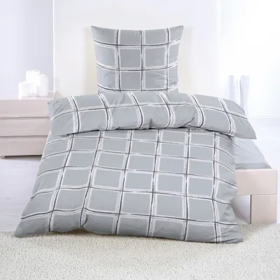 A neatly made bed with a duvet and pillow, showcasing a gray checkered pattern.
