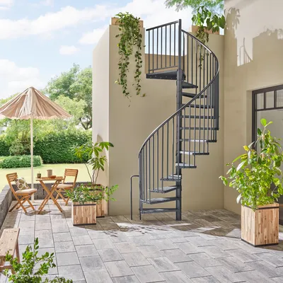 An outdoor patio with a spiral staircase, patio furniture, and potted plants.