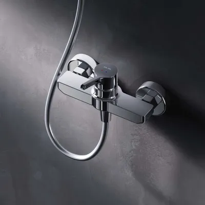 A close-up shot of a chrome shower faucet mounted on a textured gray wall.
