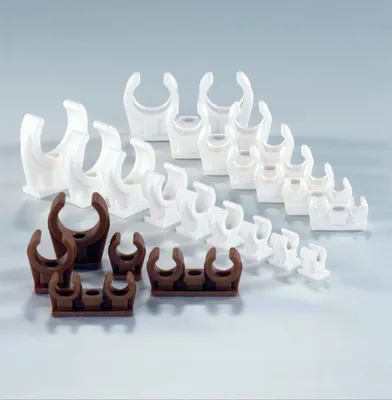 A collection of plastic pipe clips in white and brown, arranged in rows on a light gray background.