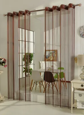 A dining area with chairs and a table, partially obscured by string curtains.