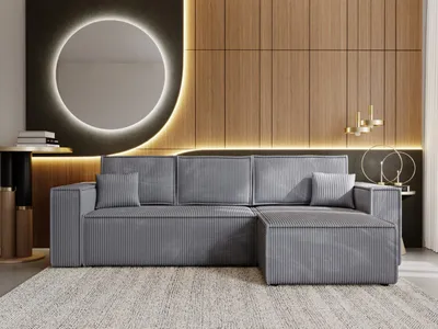 A modern living room with a grey sectional sofa, a round mirror with backlighting, and wood-paneled walls.