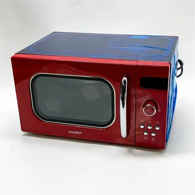 A red Comfee microwave oven is shown against a white background. The top of the microwave is covered in blue plastic wrap.