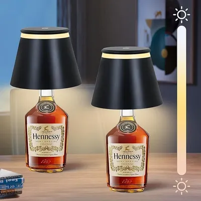 Two Hennessy cognac bottle lamps with black shades are displayed on a wooden surface, with a dimmer scale on the right.