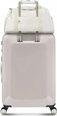 A light-colored duffel bag is placed on top of a light-colored suitcase.