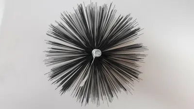 A top-down view of a chimney brush with black bristles radiating outwards from a central silver screw.