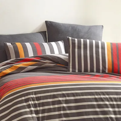 A close-up view of a striped duvet cover and pillows on a bed.