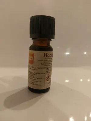 Kleine braune Flasche mit einem schwarzen Verschluss. Auf dem Etikett steht "Honig".