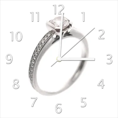 Produktbild von Wallario Design Wanduhr Silberner Verlobungsring in Nahaufnahme mit Fokussierung aus Echtglas, Größe 30 x 30 cm