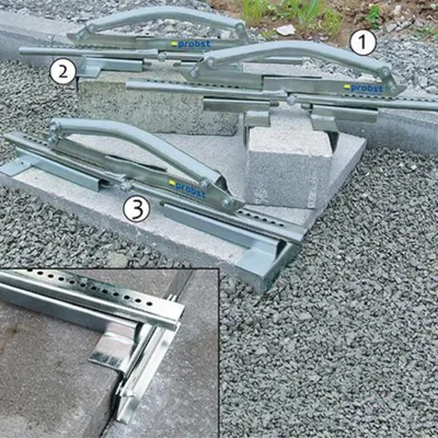 Three concrete block lifters are shown in use on a gravel and concrete block surface.
