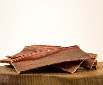 A pile of dried beef jerky pieces on a wooden surface.
