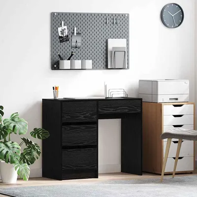 A black desk with drawers and a pegboard organizer on the wall above it.