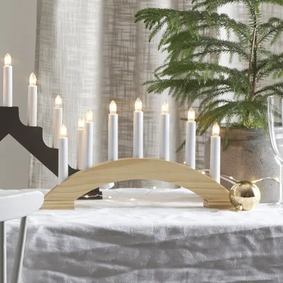 A Christmas candle arch is placed on a table with a Christmas tree in the background.