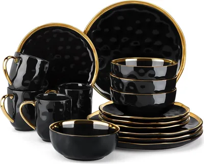 A set of black ceramic dishes with gold trim, including plates, bowls, and mugs, arranged on a white background.