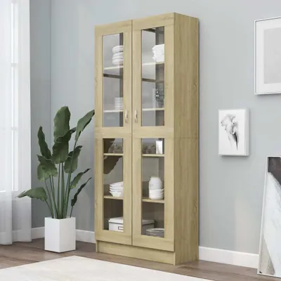 A wooden display cabinet with glass doors in a room with a light gray wall.