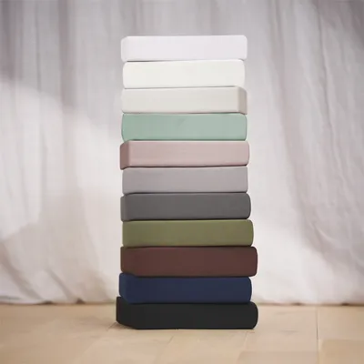 A stack of folded fitted sheets in various colors.