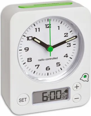 A white analog alarm clock with a green accent on top and a digital display showing 6:00.