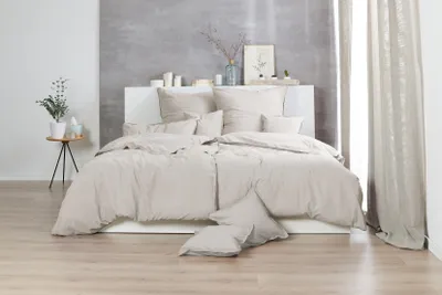 A bedroom scene with a bed made with beige bedding.