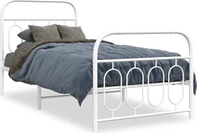 A white metal bed frame with a mattress and bedding.