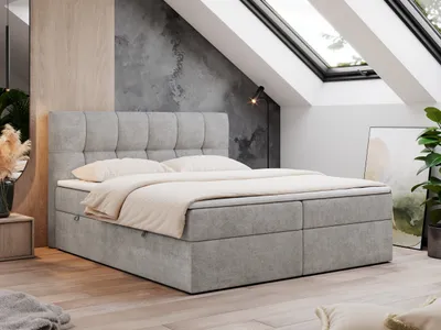 A modern bedroom with a boxspring bed under a slanted ceiling with skylights.