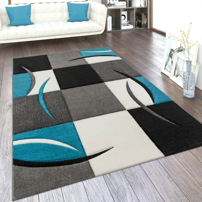 A modern living room with a white sofa, a bookshelf, and a geometric rug.